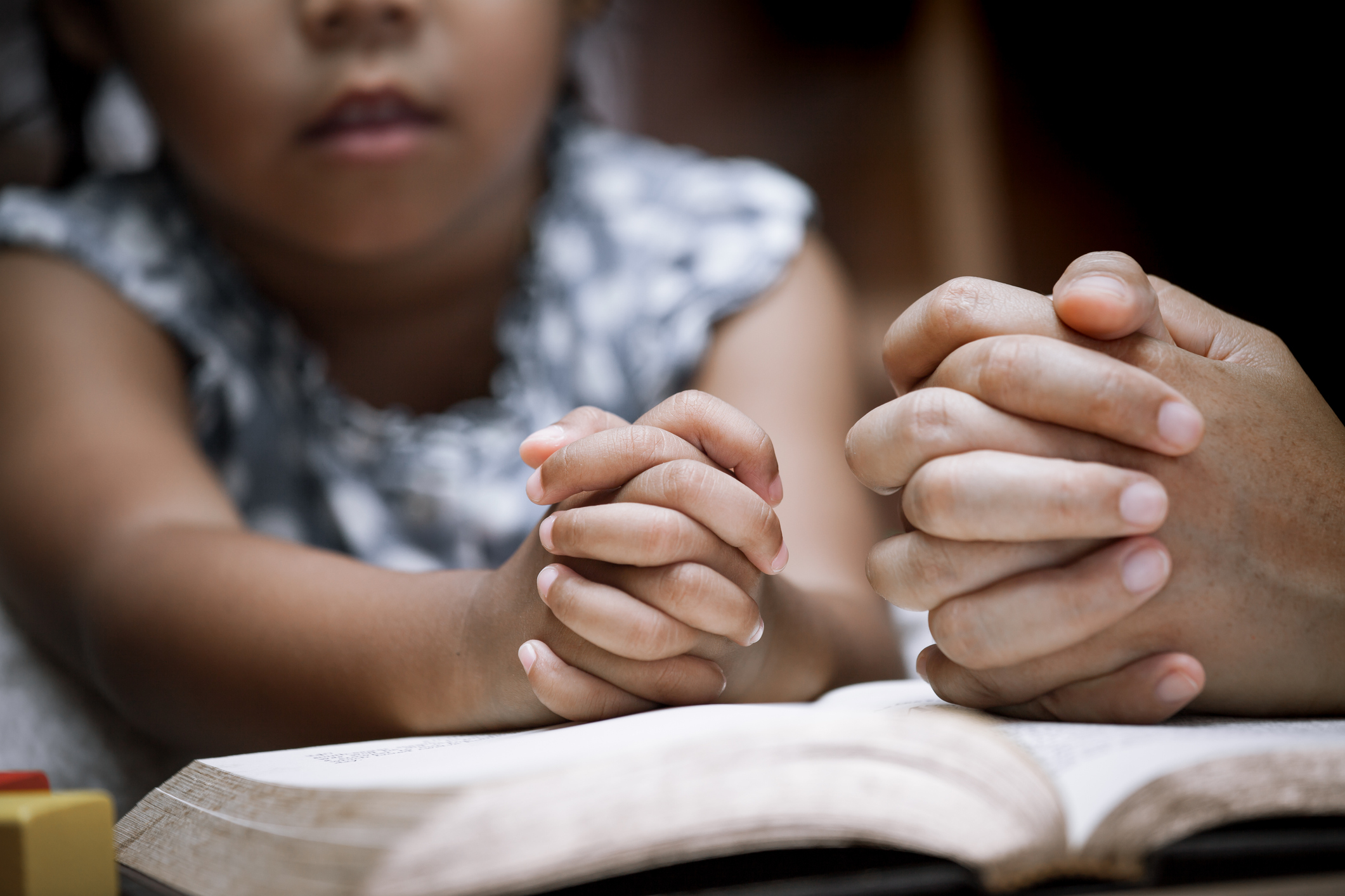 Mother and little girl hands folded in prayer on a Holy Bible together Mother and little girl hands folded in prayer on a Holy Bible together  for faith concept in vintage color tone