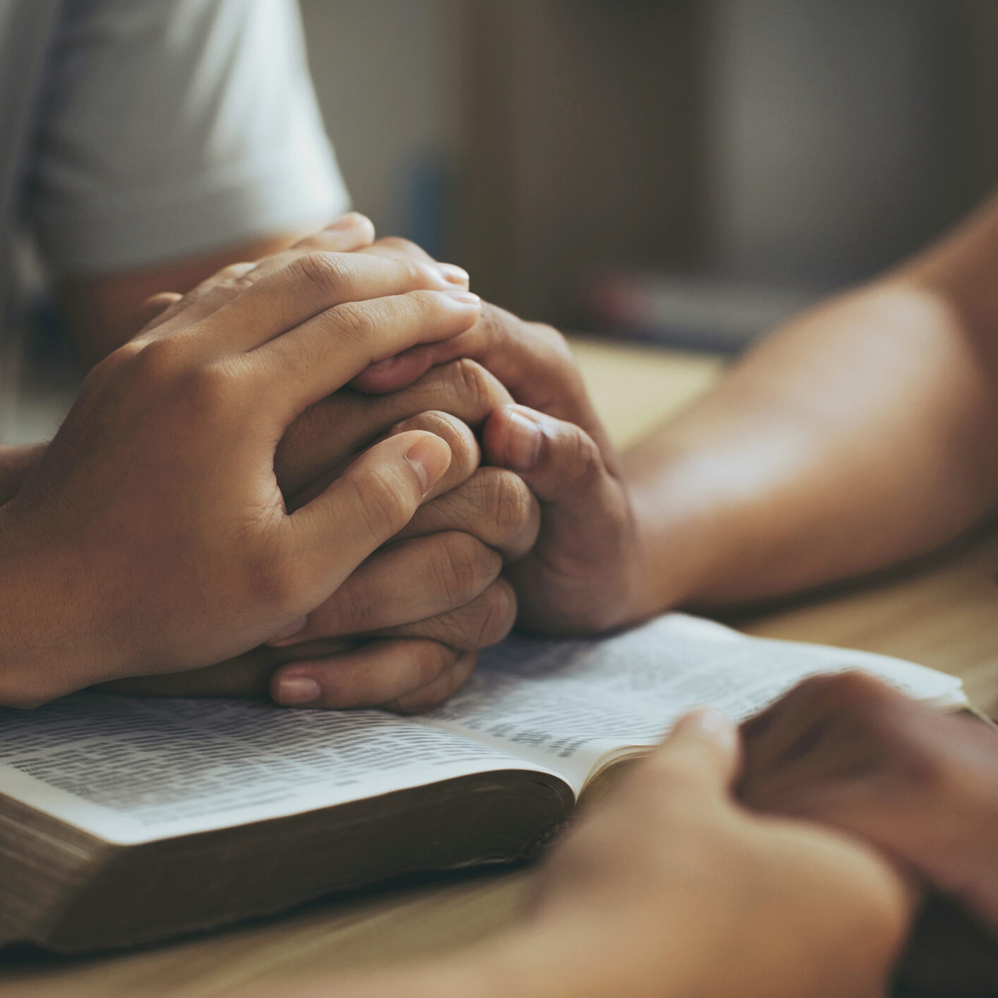 Christian group of people Holding hands together and praying on the holy bible. devotional for prayer meeting concept. praying worship to believe. Encouraging each other to get through the crisis.Love